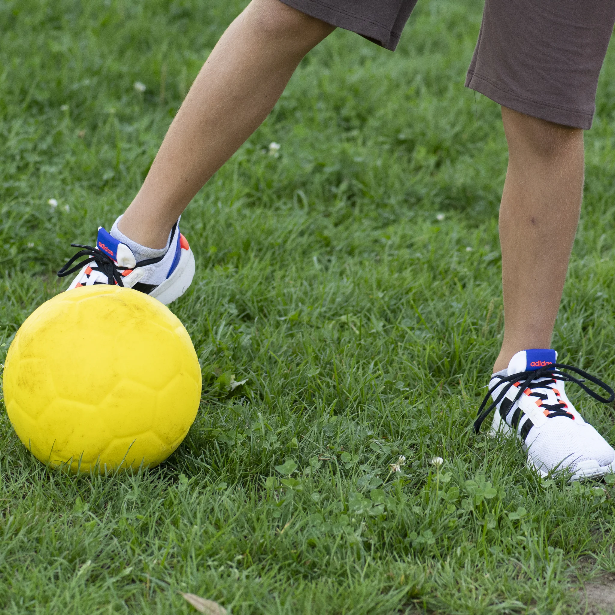 soccer ball, yellow ball, grassy field, sports shoes, foot position