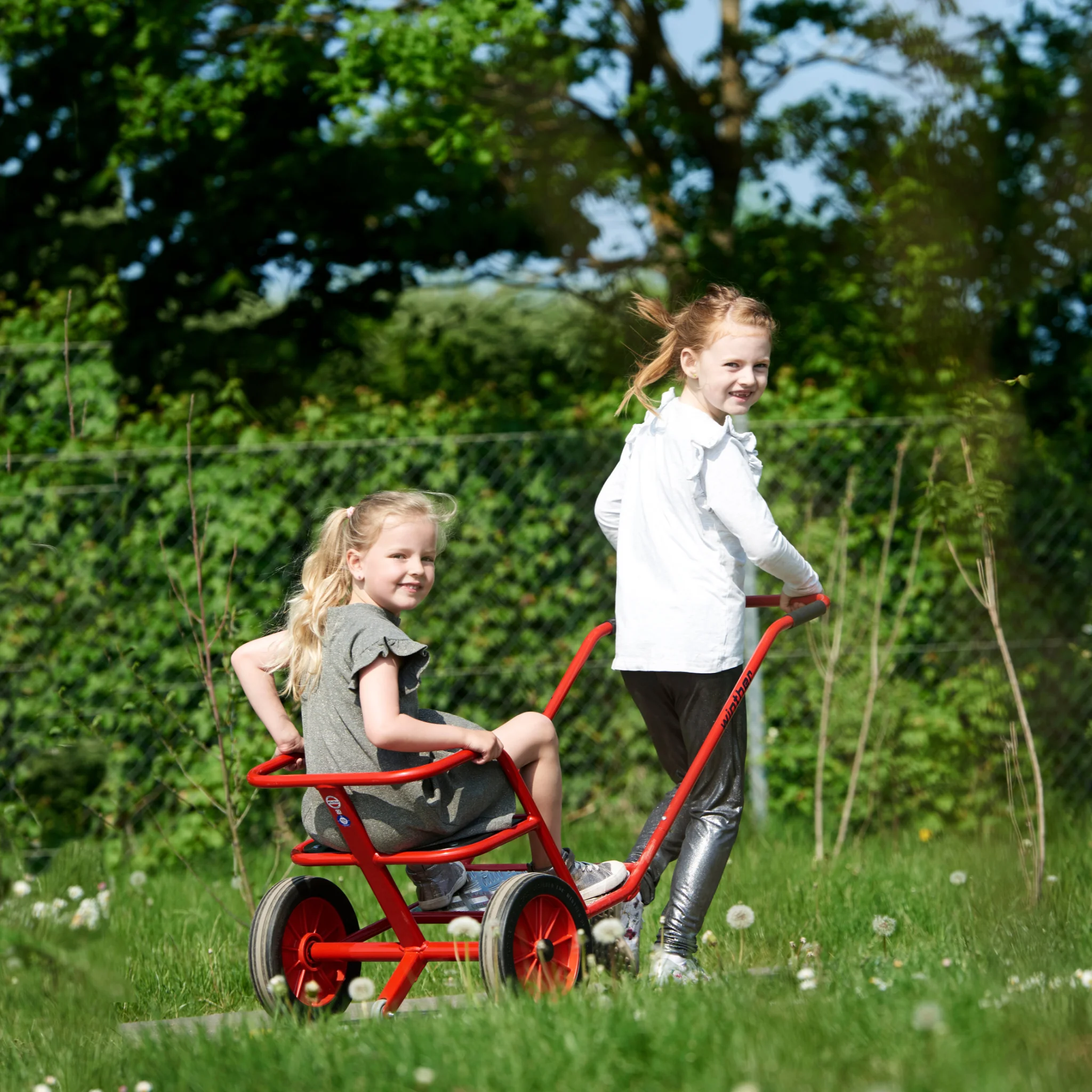 Kinderwagen, Kinderwagen mit Zugwagen, Spielende Kinder, Outdoor-Park, rote Metallrahmen