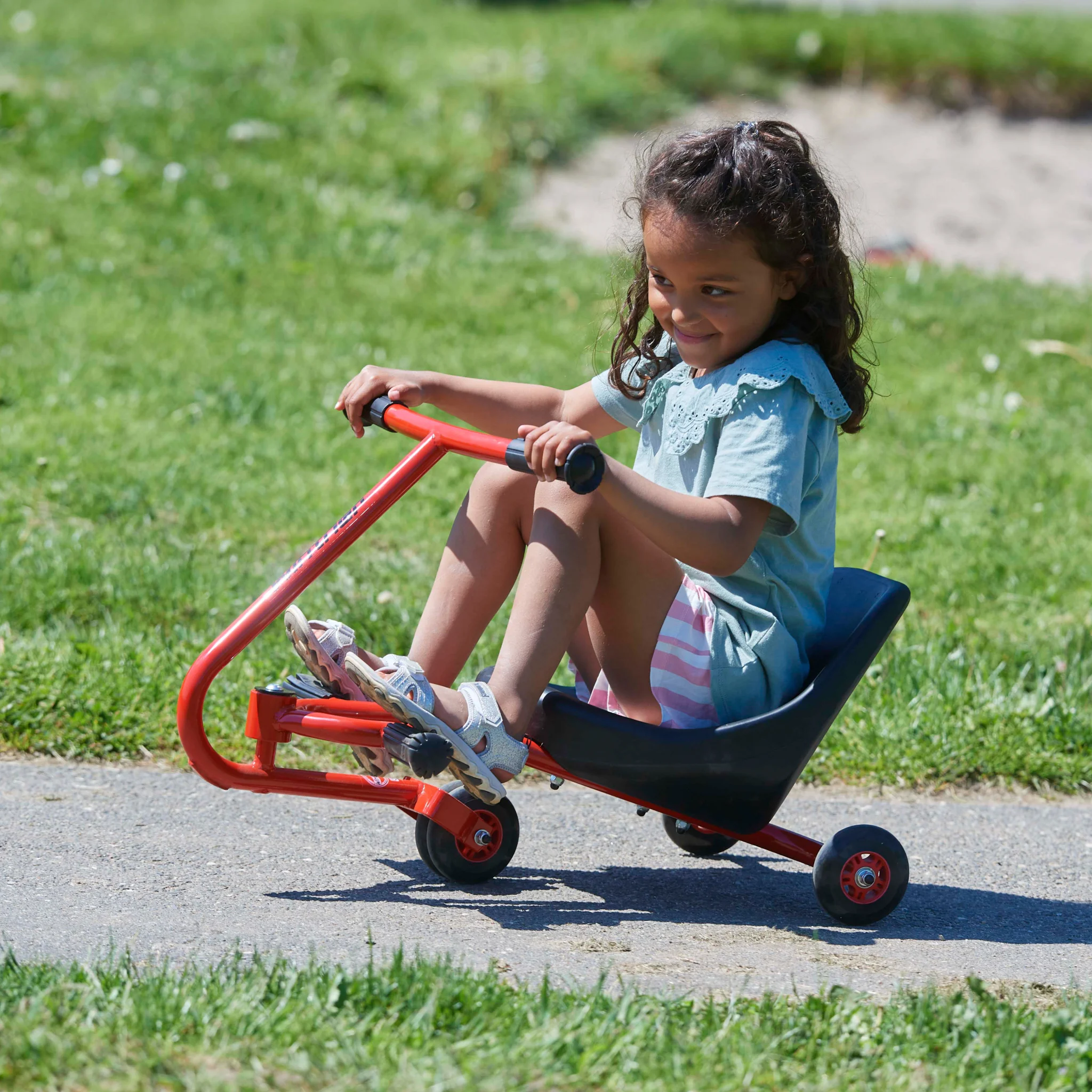 Rasentrike, Kinderfahrzeug, roter Rahmen, schwarzer Sitz, Pedalrad