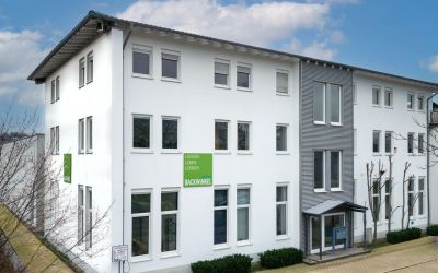 Wohngebäude, weiße Fassade, Mehrfamilienhaus, große Fenster, grünes Schild